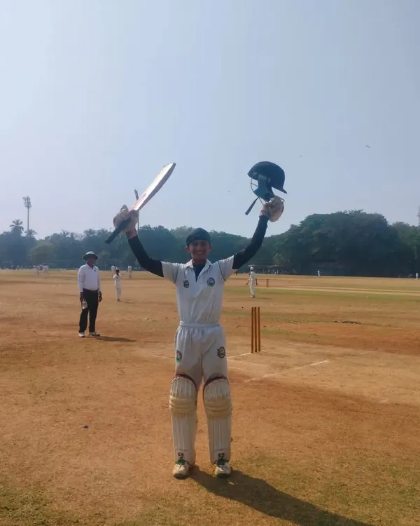 This is the moment every cricketer dreams of. A young batsman celebrating a hard-earned milestone on the field, raising his bat and helmet in triumph. This is what we train for.