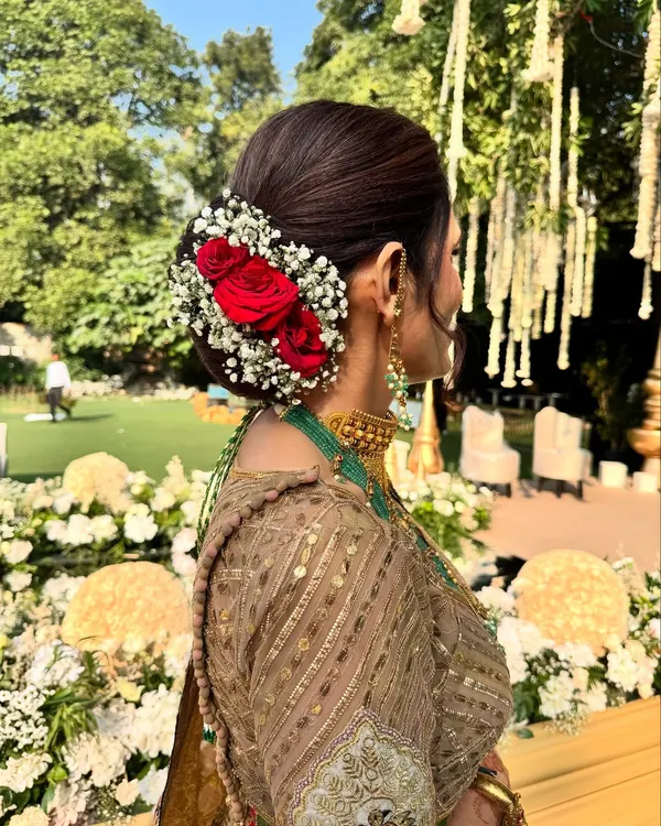 A close-up of the elegant floral bun we created for the mother of the groom. Fresh red roses and baby's breath make for a timeless and classic wedding hairstyle.
