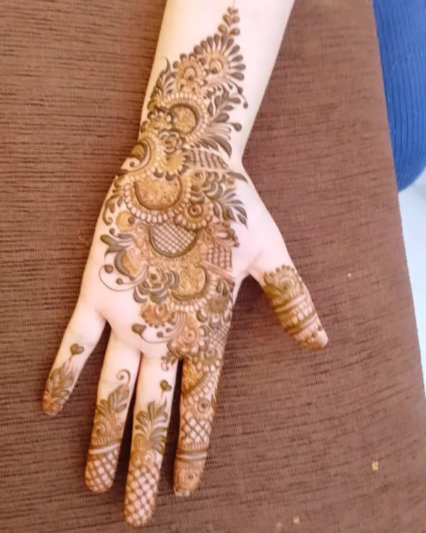 A classic Arabic style mehndi design. The pattern flows diagonally across the back of the hand, featuring floral and paisley elements with shaded details.