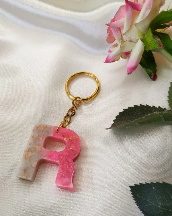 A custom initial keychain made with a beautiful blend of pink and pearl white resin, with a touch of gold flakes for sparkle.