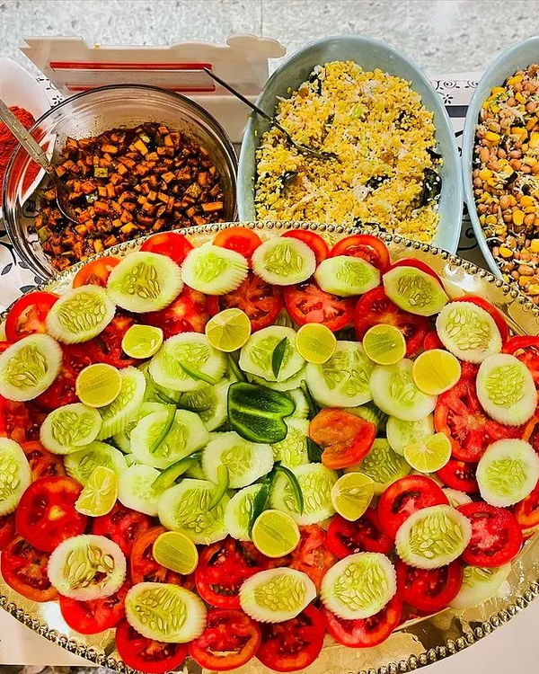 A fresh and colourful salad platter, featuring sliced tomatoes, cucumbers, and lemon. Alongside are bowls of kosambari and other healthy preparations, perfect for a light and healthy option.