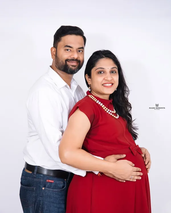 A classic couple's portrait against a clean white background. This style is timeless and puts all the focus on the expecting parents' happy expressions and connection.