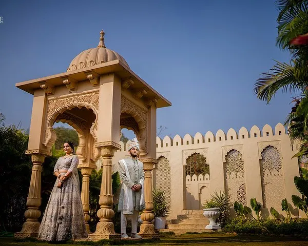 A majestic portrait of Yash and Priyanshi in traditional Indian wear, standing beside a beautiful stone cenotaph. This shot captures the essence of royal Rajasthani architecture and elegance.