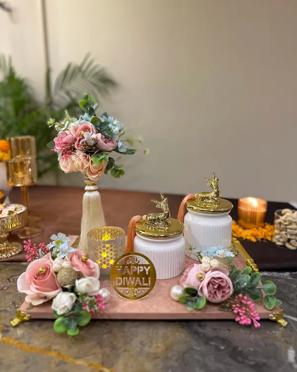 A beautiful Diwali hamper featuring a marble-finish tray, elegant deer-topped jars, and a floral bouquet. This set is designed to bring a touch of modern elegance to your festive gifting.