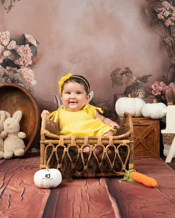Halfway to one. This happy sitter-session baby is celebrating her six-month milestone with a bright yellow outfit and a charming rustic backdrop.