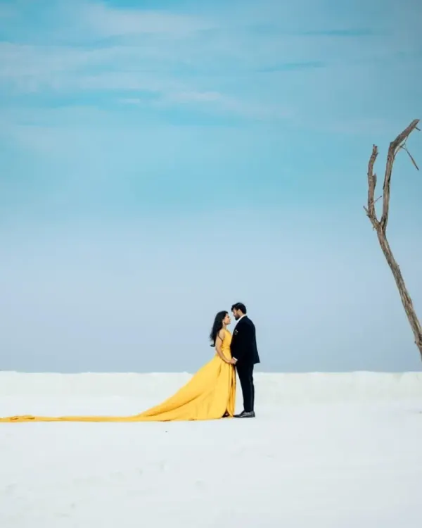 Create an unforgettable pre-wedding moment with our vibrant yellow trail gown. Its incredibly long train flows beautifully, creating a dramatic contrast against any landscape, like this minimalist white sands location. This is one of our most requested looks for couples wanting a film-style photoshoot.