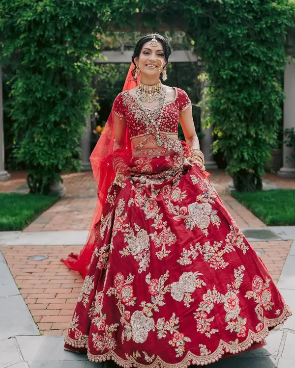 A classic red bridal lehenga never goes out of style. Here, the intricate silver and gold floral embroidery by Dolly J Studio creates a look of pure elegance.