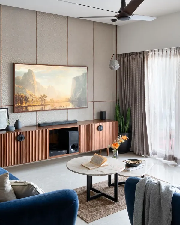 This living room from our "Timeless Tranquility" project is the perfect example of our design philosophy. We focused on creating an open, airy layout filled with natural light, using a mix of warm wood textures, a comfortable blue sofa, and clean wall paneling to create a space that is both stylish and incredibly livable.