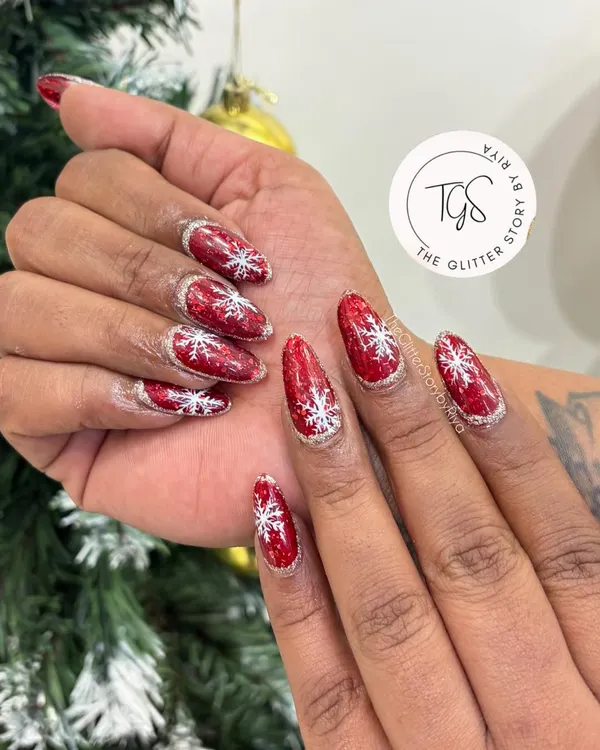 Get into the holiday spirit with these festive Christmas nails, featuring a bold red glitter base with hand-painted white snowflakes.