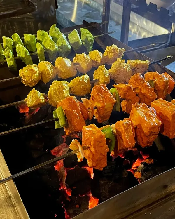 Who can resist the aroma of a sizzling barbecue? Here are skewers of Paneer Tikka and other marinated vegetables grilling over hot coals, getting that perfect smoky char.