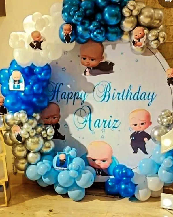 A Boss Baby theme is perfect for a little one turning one. This setup for Aariz's first birthday featured a custom circular backdrop with character cutouts, a blue and silver balloon arch, and baby blocks for a playful touch.