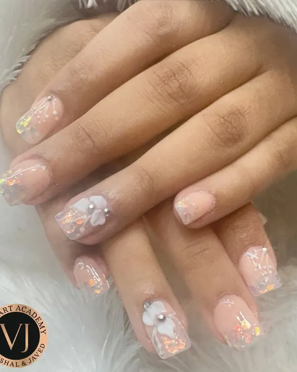 The perfect look for a bride or a festive occasion. These delicate nude nails feature iridescent flakes and 3D floral accents for a touch of dreamy elegance.