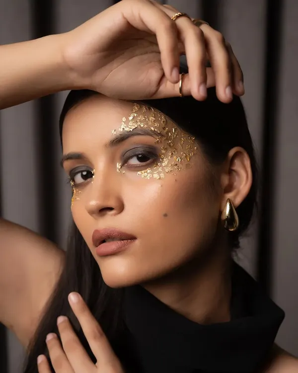 This is a hero beauty shot from a model's portfolio session, featuring creative makeup with gold leaf. I use focused lighting to highlight the intricate details and create a striking, high-fashion look perfect for editorial submissions.