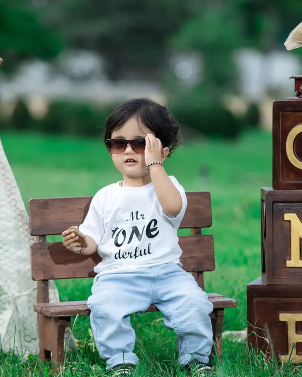 This 'Mr. ONEderful' is looking cool in his sunglasses during his outdoor birthday shoot. The natural light and greenery make for a beautiful portrait.