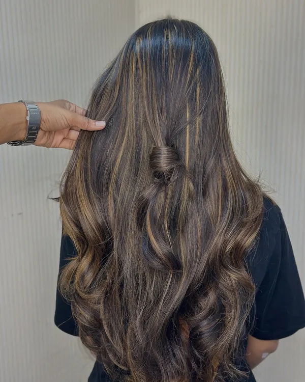 A look at the details of our balayage work. Notice how the highlights are perfectly blended to create dimension, shown here with soft waves and a stylish half knot.