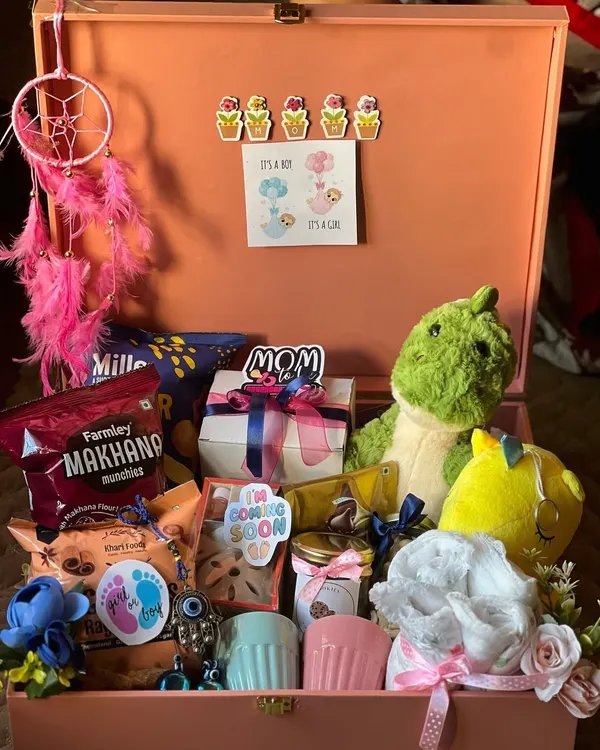 This large trunk box is one of my favorite creations for a mom-to-be. I filled it with a mix of practical and fun items, including healthy makhana snacks, cozy baby booties, a cute dinosaur plushie, and matching mugs for the new parents.