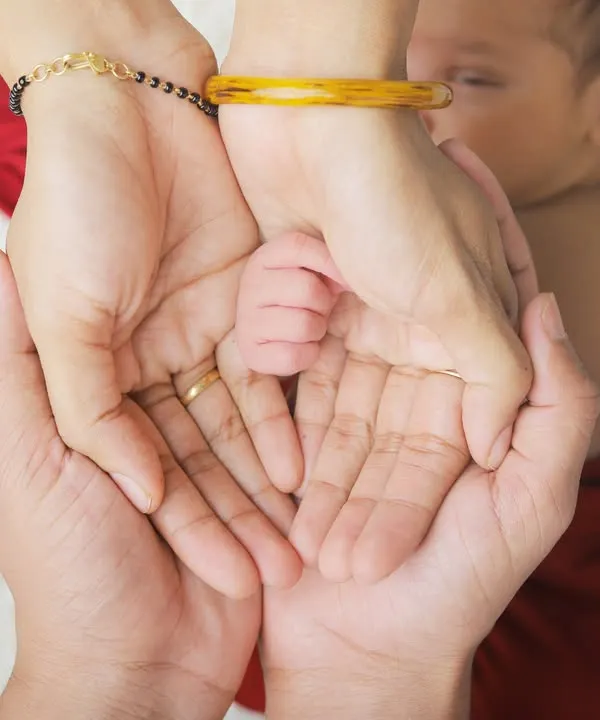 A tiny newborn hand held securely in the loving palms of its parents. This detailed shot is a powerful reminder of how small they once were.
