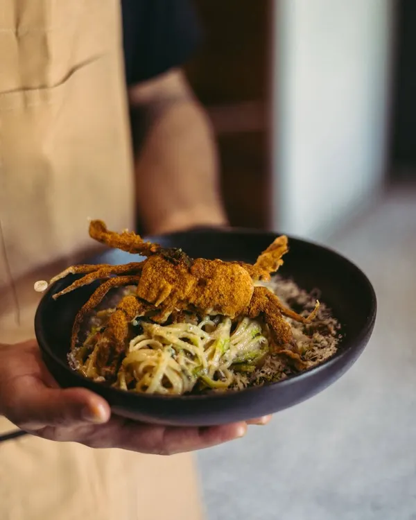 This is where pasta tells a story of the coast. I toss handmade linguine with roasted chili, garlic, and olive oil, then top it with a whole crispy soft-shell crab. It’s a dish that’s both familiar and exciting, bringing a taste of the sea to your table.