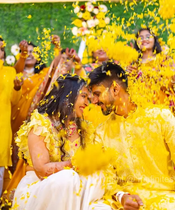 A candid moment of pure celebration as the couple is showered with yellow petals during their Haldi ceremony. I focus on capturing the unfiltered energy and vibrant colors that make these events so memorable.