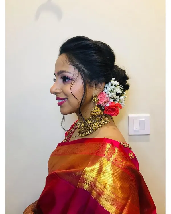 A beautiful example of a classic reception hairstyle. This elegant, low floral bun is adorned with fresh roses and baby's breath, creating a look that is both romantic and sophisticated.