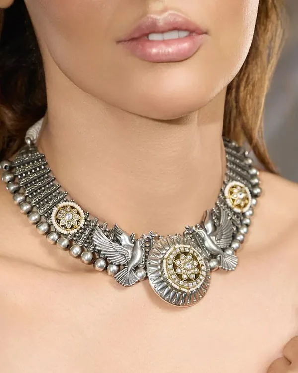 An heirloom of elegance, crafted to perfection. This oxidized silver choker features dove motifs and floral polki medallions, blending strength with delicate details.