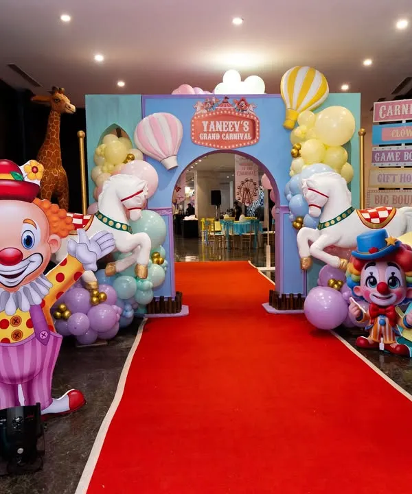 A spectacular grand entrance to a carnival party, featuring a red carpet, clown and animal props, and a personalized archway.