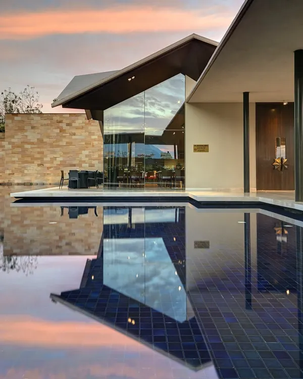 The Lotus Cafe at the Dasavatara Hotel in Tirupati, where the modern, angular roof reflects on the water at dusk, creating a dialogue between the structure and its environment.