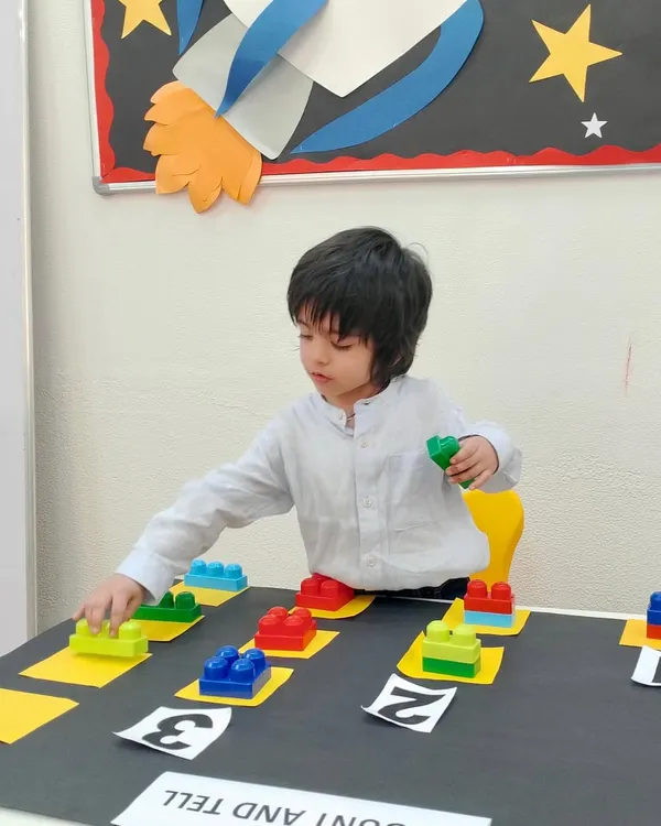 A student carefully places blocks during our "Count and Tell" activity. This hands-on approach to math helps children visualize quantities and connect them to numerals, making abstract concepts concrete.
