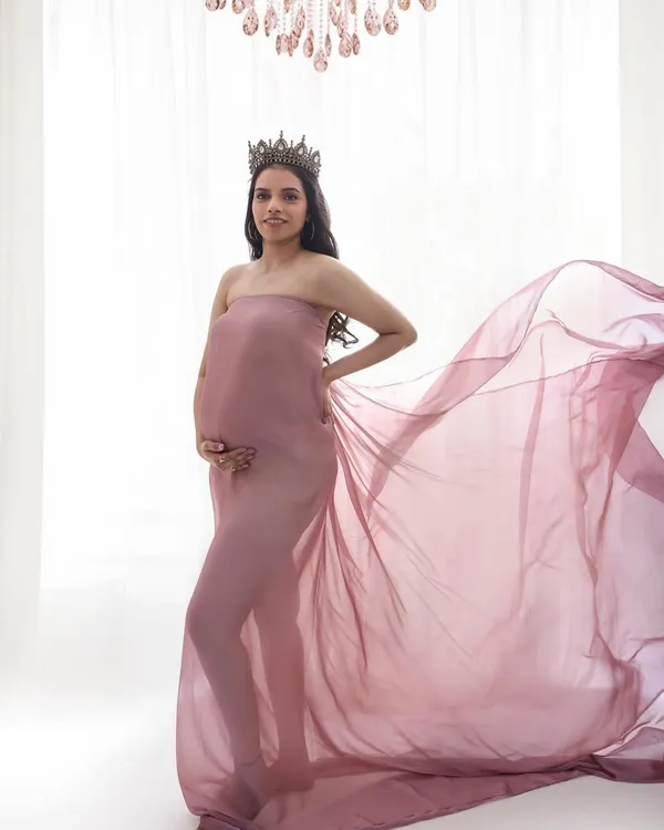 A queen awaiting her heir. This maternity shoot look is all about ethereal beauty, with soft, glowing makeup and a flowing gown to create a truly magical portrait.