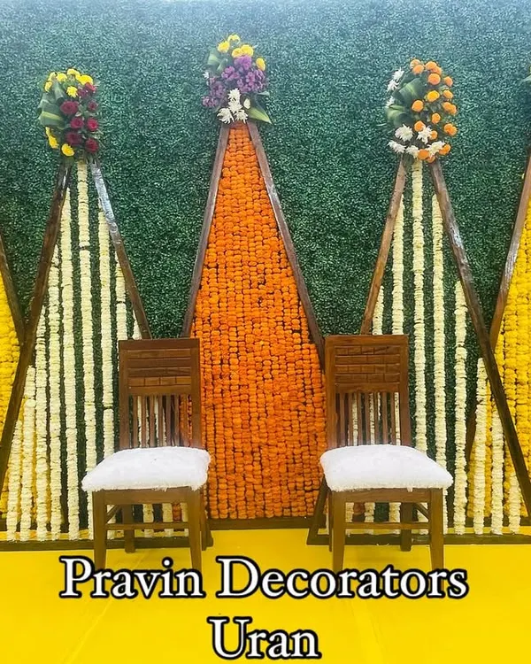 A vibrant Haldi backdrop made with a green foliage wall and geometric panels filled with yellow and orange marigolds. This setup uses fresh, original flowers to bring a traditional and colorful energy to the ceremony.