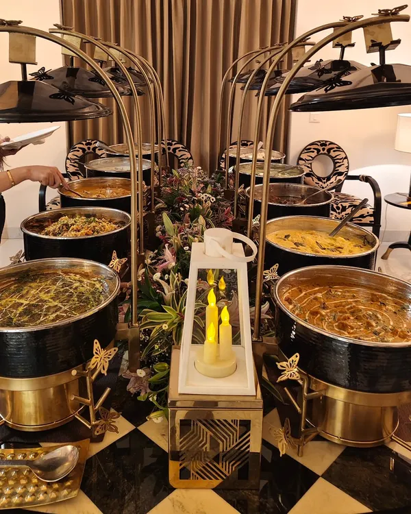 A stunning buffet setup featuring our signature black and gold chafing dishes, elegant floral arrangements, and ambient candle lighting. We design every detail to create a sophisticated and cohesive look for your event.