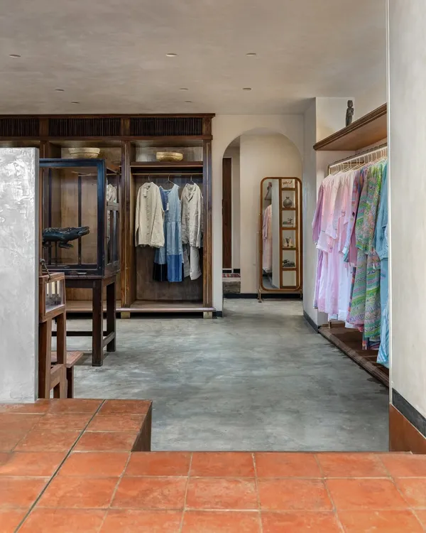 A view from the terracotta-tiled courtyard into the main retail space at Eka. The transition to a polished concrete floor marks a shift to a more intimate atmosphere, where custom wood wardrobes and antique displays showcase the clothing.
