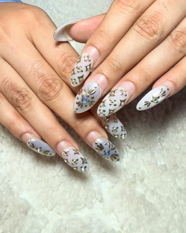 An incredibly detailed and luxurious design. These almond-shaped extensions feature a subtle logo pattern with carefully placed gold and blue rhinestones for a high-fashion look.