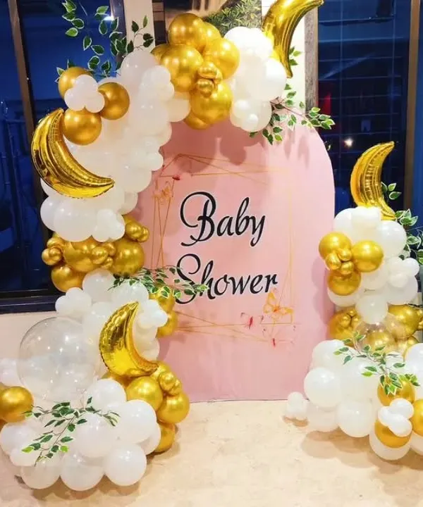 A dreamy "Baby Shower" decoration with a "Twinkle Twinkle Little Star" vibe. This setup features a pink arched backdrop, a white and gold balloon garland, and crescent moon foil balloons.