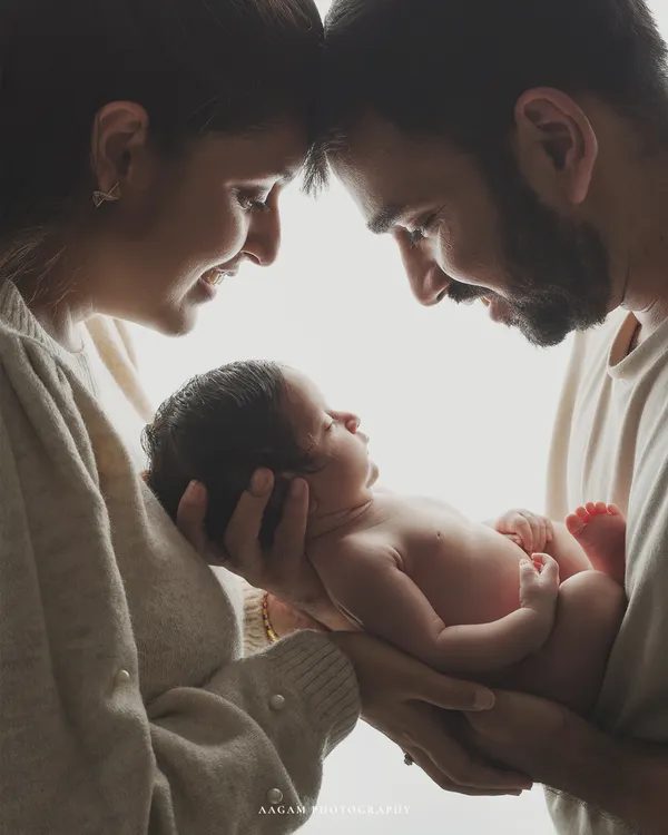 A family born in one magical moment. This intimate portrait captures the awe and love as new parents gaze at their baby, held securely in their hands.