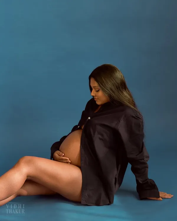 A quiet and intimate moment from a maternity session. The simple styling with an open shirt creates a raw and beautiful portrait, celebrating the natural form of pregnancy.
