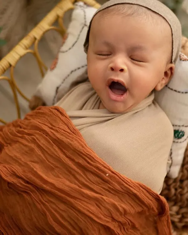 A big sleepy yawn! I love catching these candid moments. This little one is tucked into a wicker basket with soft blankets, perfectly safe and cozy for a nap.
