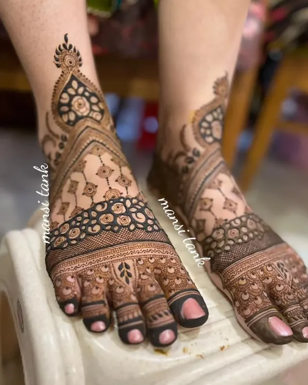 This is a full coverage bridal foot mehendi. The intricate design flows from the toes all the way up past the ankle, creating a stunning look that is perfect for a bride.