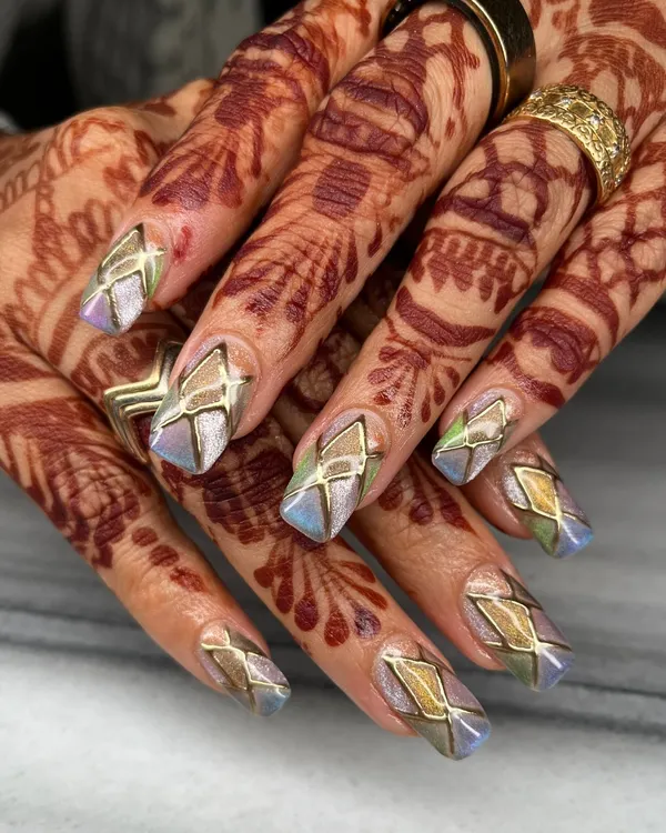 This intricate design features multi-tonal chrome with geometric gold outlines on long coffin nails. The way the colors shift makes this set captivating from every angle, especially against the henna.