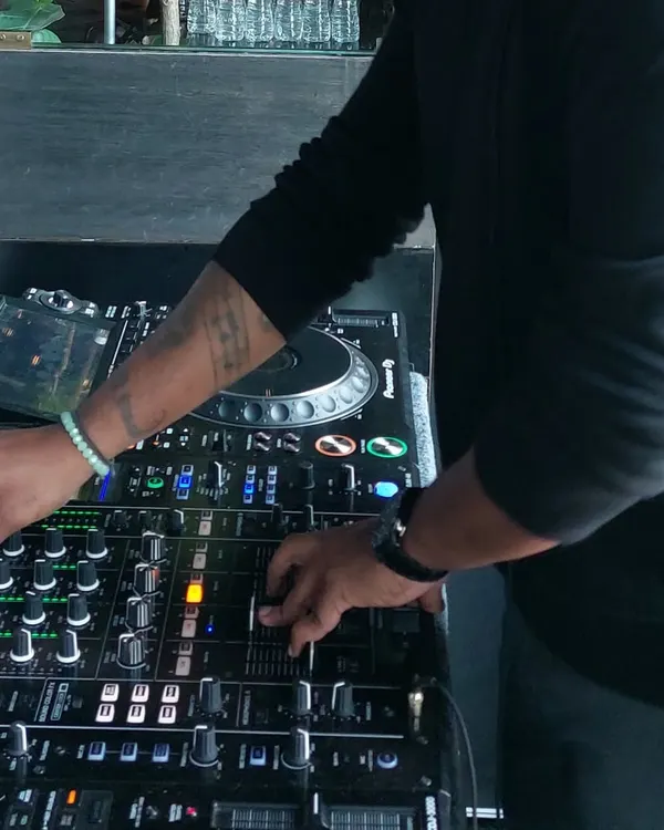 A close-up shot of my hands on the Pioneer DJ mixer. This is where the magic happens, as I blend tracks, control levels, and add effects to create a seamless musical journey.