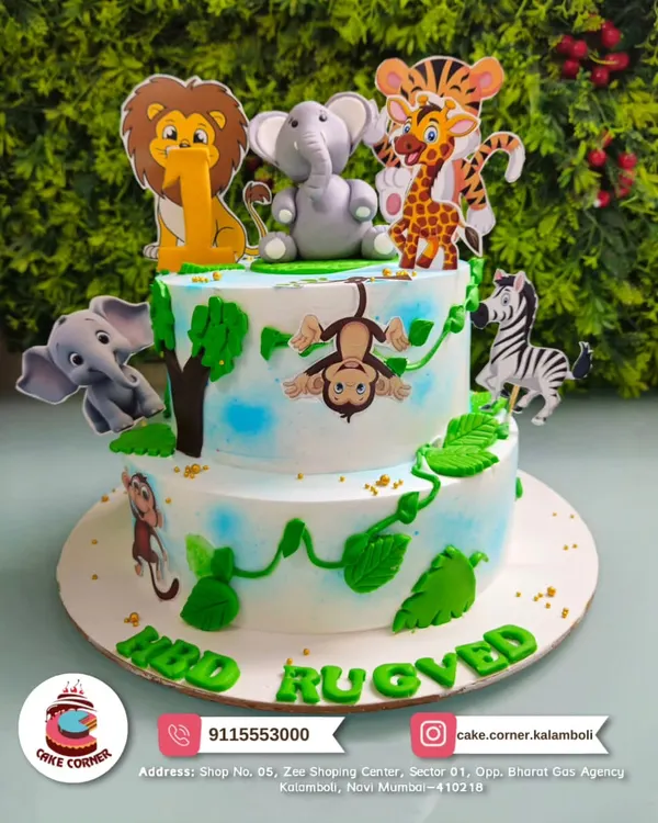 A wild two-tier jungle theme cake for Rugved's birthday. It's full of friendly animals like a lion, elephant, monkey, and zebra, perfect for a little explorer.