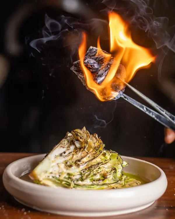 I like to add a little theater to my dishes. The Manor Caesar salad gets a smoky twist from a piece of burning charcoal, infusing the crisp lettuce with a unique, aromatic flavor right at your table.