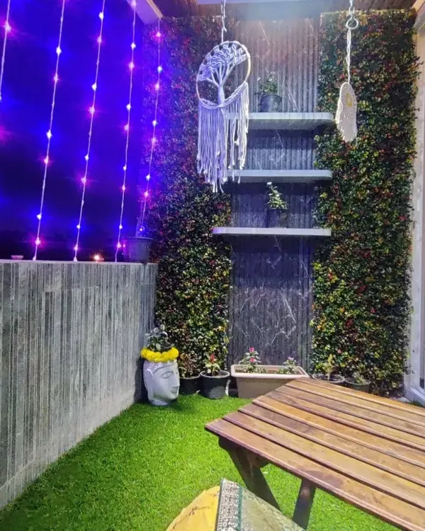 We transformed this balcony into a cozy evening retreat. Artificial turf on the floor, green walls for privacy, and soft curtain lights create a magical ambiance, perfect for relaxing after a long day.