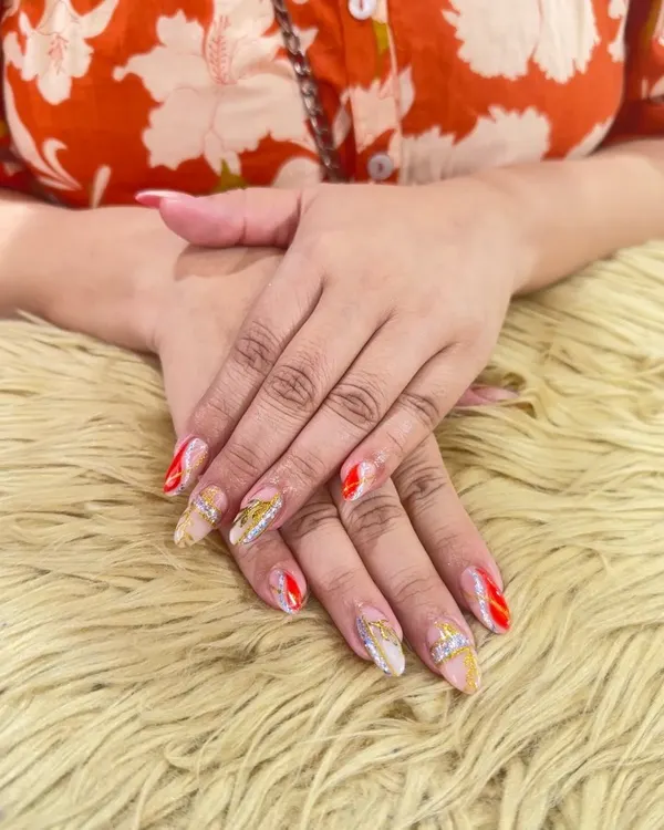 A stunning set of bridal nails designed to make a statement. This look features a mix of sheer nude, bold red, and sparkling silver glitter, with delicate gold leaf details for an extra touch of luxury.