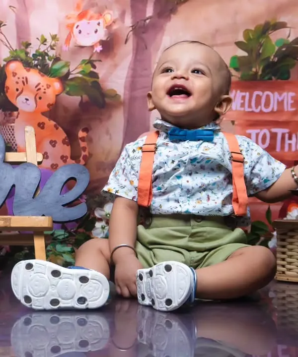 A joyful first birthday photoshoot with a jungle theme. The 'ONE' sign and happy expression make this a perfect milestone memory.