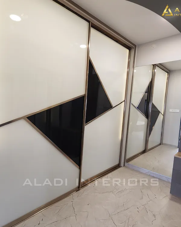 A modern sliding wardrobe with a striking geometric pattern in black and white glass, framed with a gold finish. This piece is both a functional storage unit and a bold design statement.