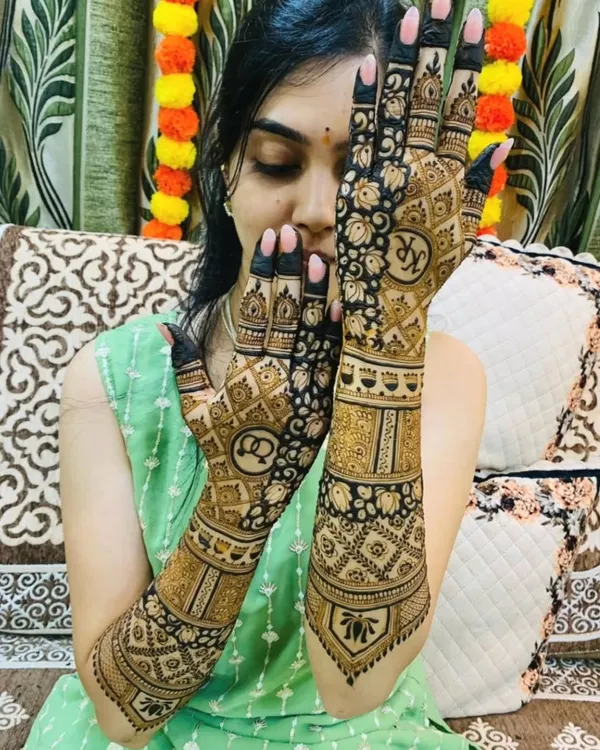 A playful pose showing off a beautiful bridal design that incorporates the couple's initials, "KR" and "AS," inside elegant circular frames on the palms.