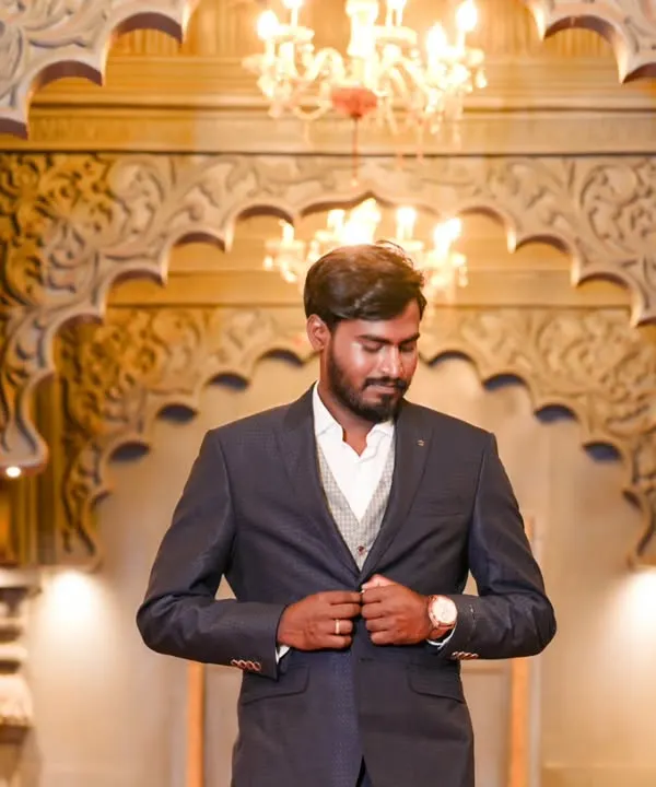 A handsome portrait of the groom-to-be, looking sharp in his suit. The grand, warmly lit hall provides an elegant backdrop for this solo shot.