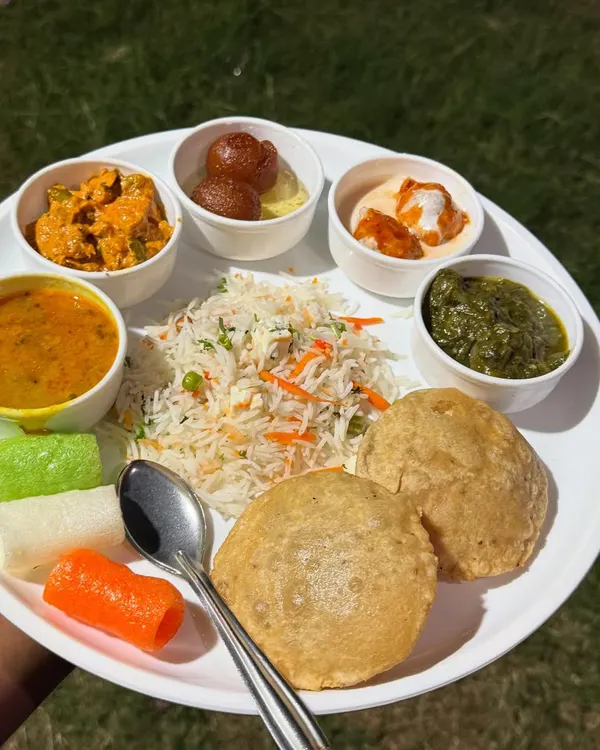 A complete, pure vegetarian meal plated to show you the variety I offer. This particular thali is a Jain meal, featuring vegetable pulao, soft puris, dal, paneer sabzi, and gulab jamun, all prepared without onion or garlic.