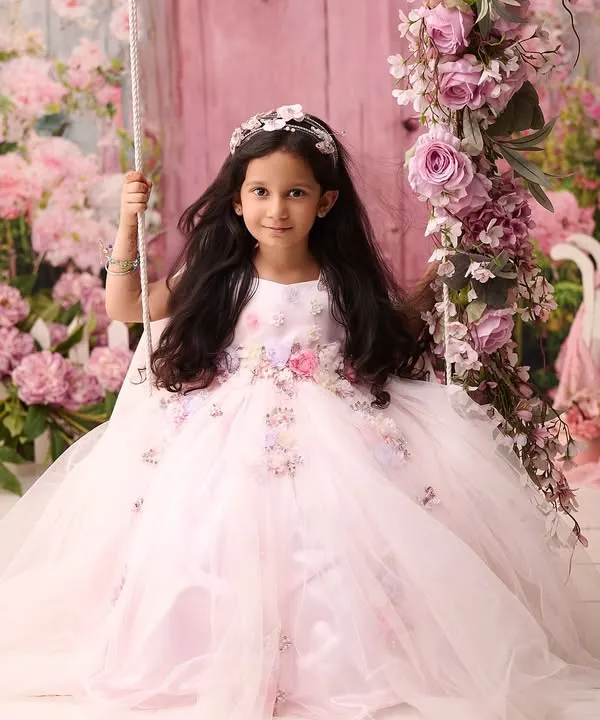 A fairytale moment comes to life with this portrait of a young girl on a swing adorned with pink flowers. Our elaborate studio setups are designed to make every child feel like they are in a magical story.